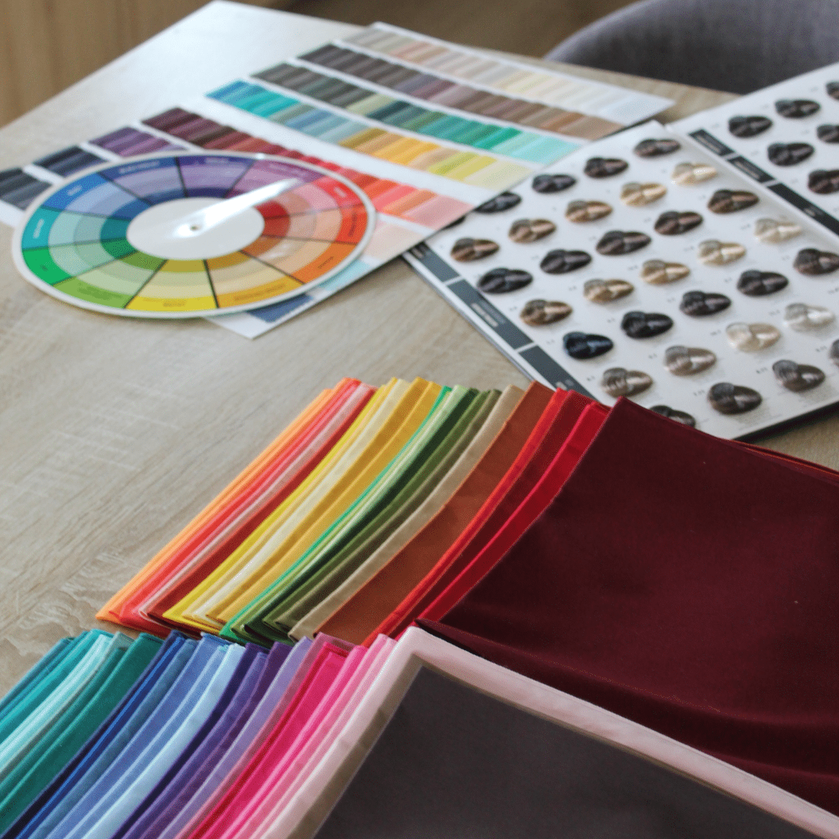 Roue chromatique, palettes et drapings colorés disposés sur une table lors d'un atelier de colorimétrie